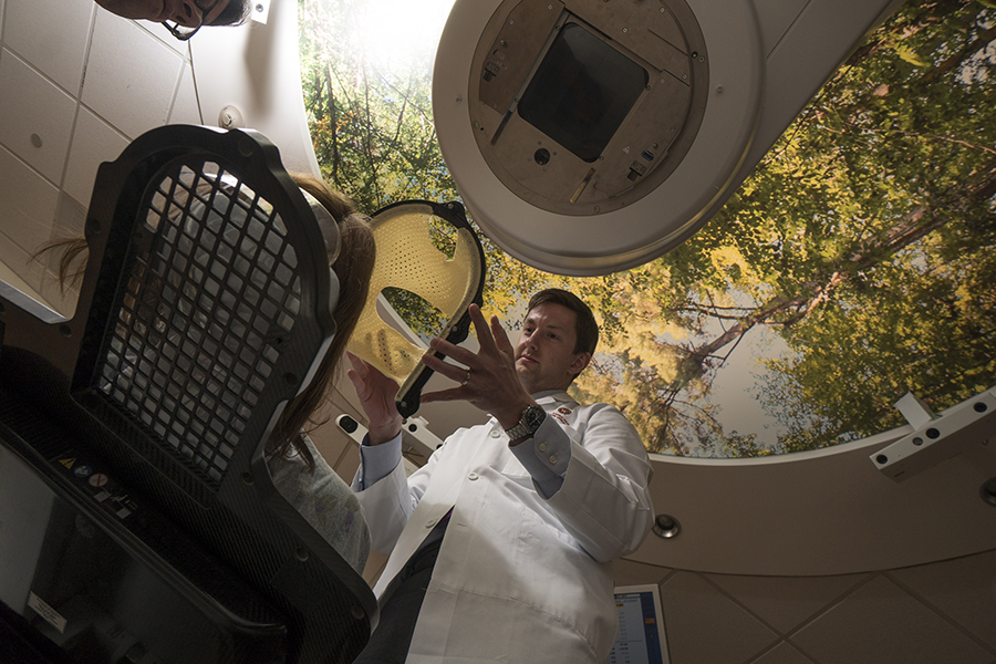 Dr. Zac Labby, assistant professor in the Department of Human Oncology, assistant professor in the Department of Human Oncology, demonstrates placement of the plastic face mask used for frameless stereotactic radiosurgery
