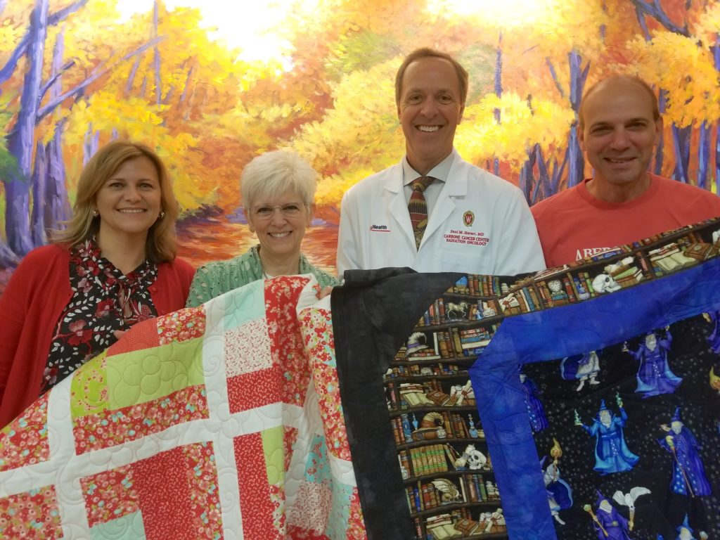 Janet Nanni, Denise Wright, Dr. Paul Harari and Peter Nanni display a couple of quilts donated to UW Radiation Oncology Clinic