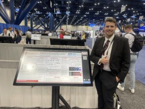 Photo of Nicholas Summerfield with his poster in convention room